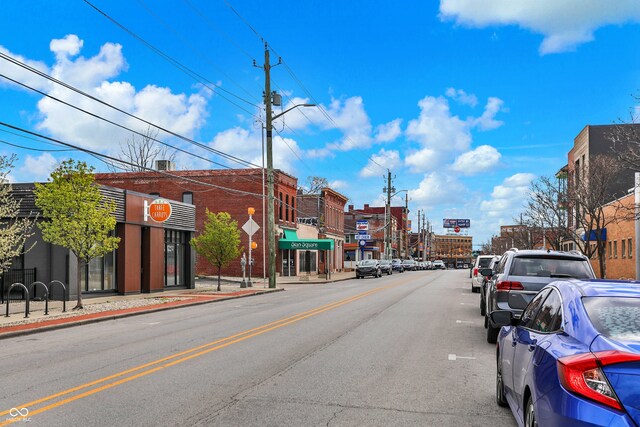 view of road featuring sidewalks, curbs, street lighting, and traffic signs