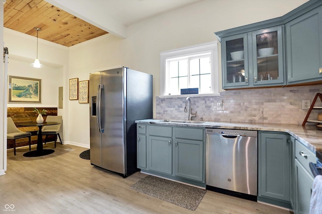 kitchen with beam ceiling, a sink, appliances with stainless steel finishes, light wood-type flooring, and backsplash