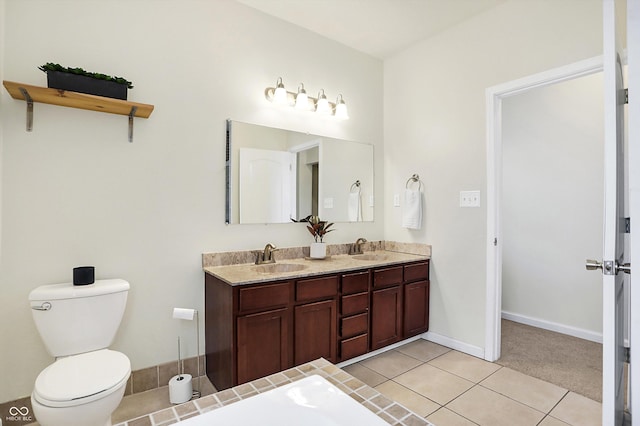 full bathroom with baseboards, double vanity, a sink, tile patterned flooring, and toilet