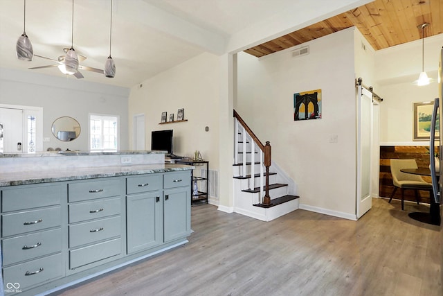 kitchen featuring visible vents, gray cabinetry, a barn door, light wood-style floors, and a ceiling fan