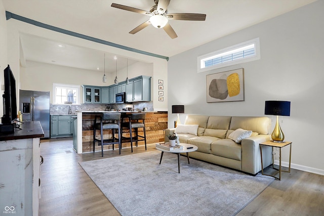 living room with baseboards, light wood-style floors, and a ceiling fan