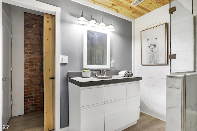 bathroom featuring vanity, wood finished floors, visible vents, brick wall, and wood ceiling