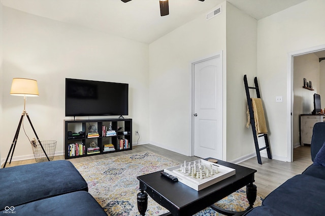 living area featuring visible vents, baseboards, a ceiling fan, and wood finished floors