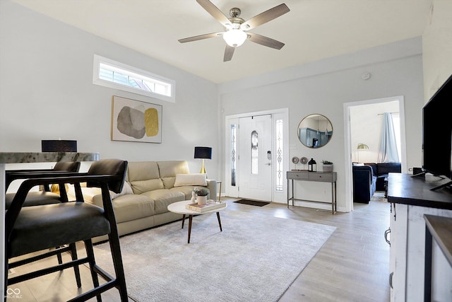 living area with light wood-type flooring, baseboards, and ceiling fan