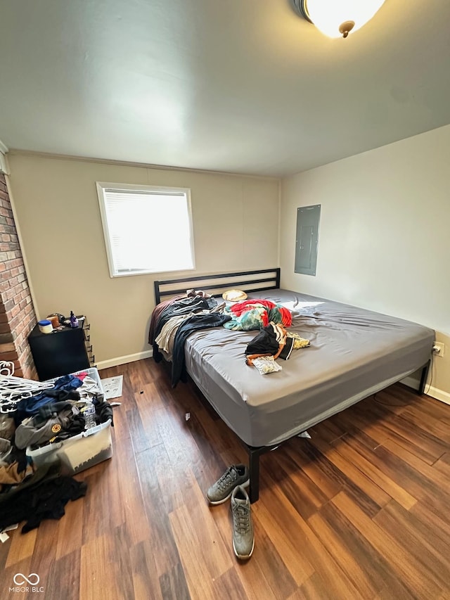 bedroom with electric panel, baseboards, and wood finished floors