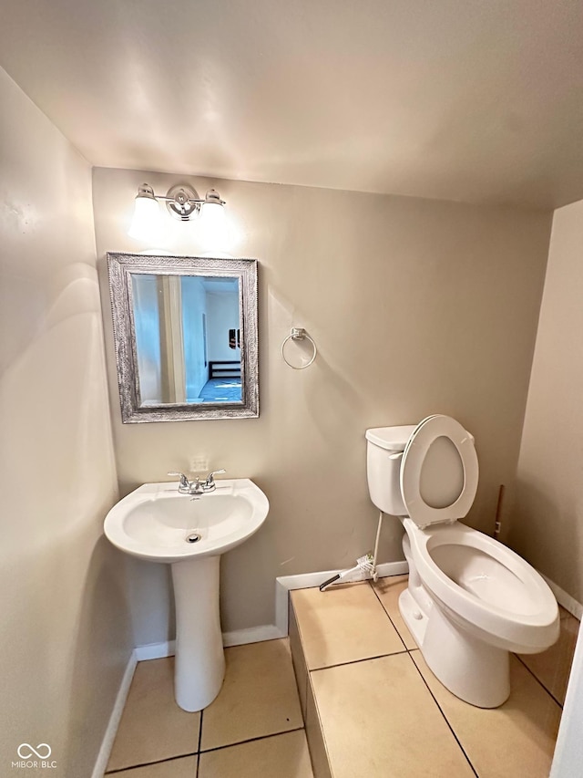 half bathroom with tile patterned flooring, toilet, and baseboards