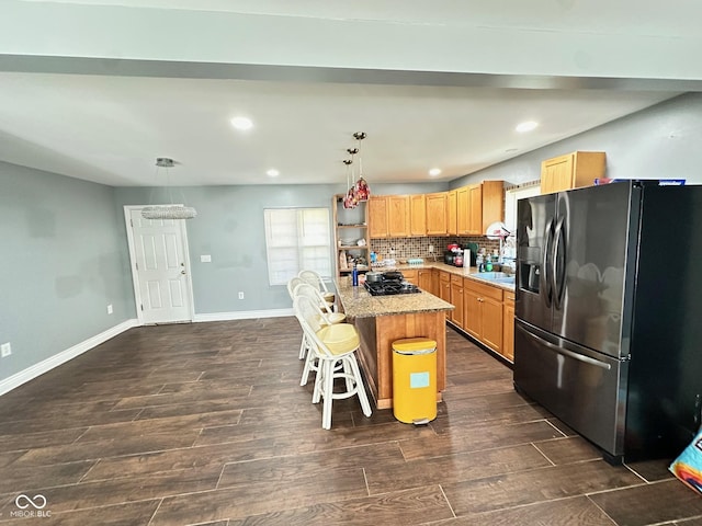 kitchen featuring dark wood finished floors, a sink, light countertops, stainless steel fridge, and tasteful backsplash