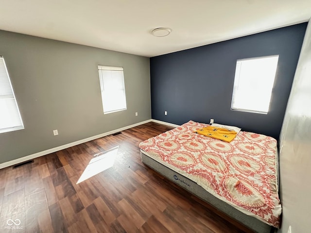 unfurnished bedroom featuring visible vents, baseboards, and wood finished floors