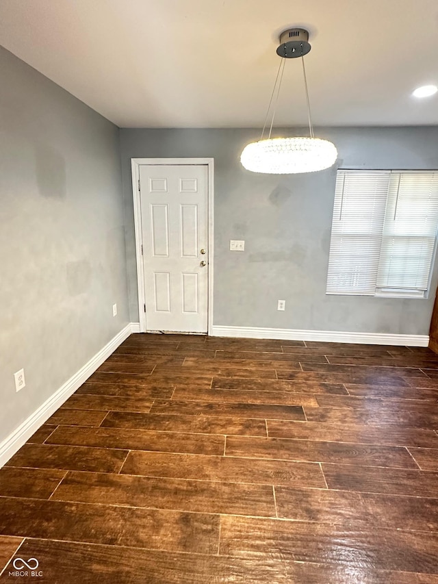 spare room with baseboards and wood finished floors