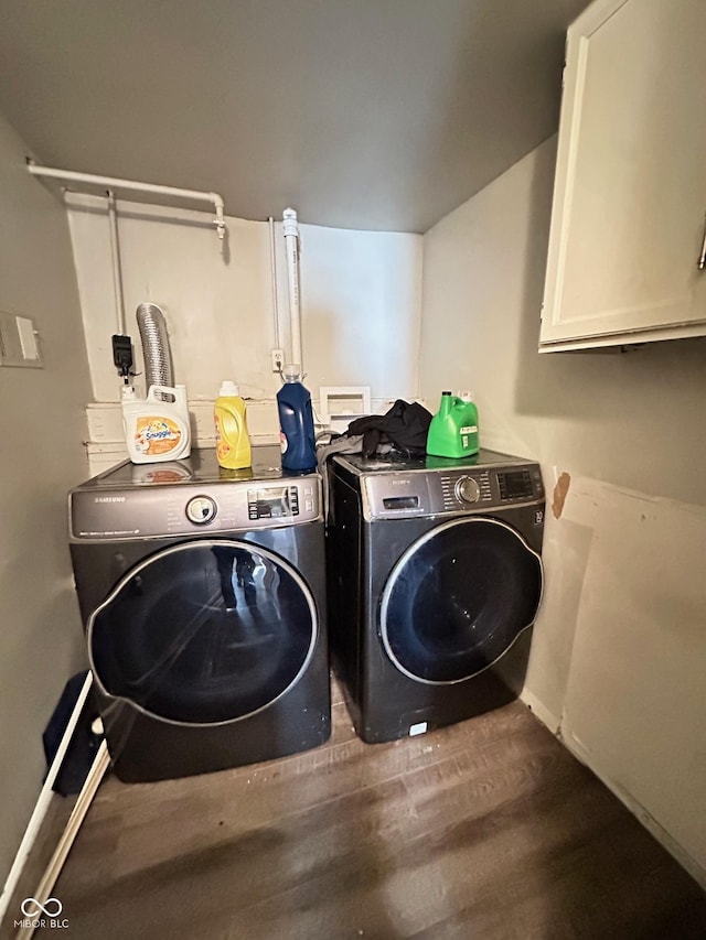 clothes washing area featuring cabinet space, wood finished floors, and washing machine and dryer