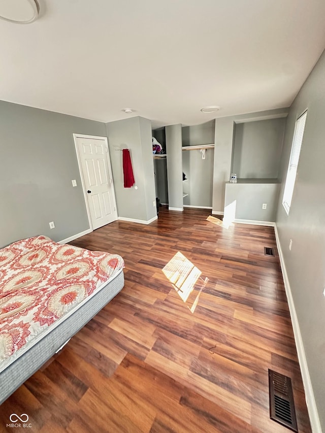 unfurnished bedroom with visible vents, baseboards, and wood finished floors