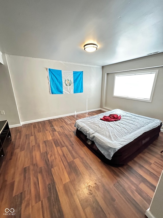 bedroom with wood finished floors, visible vents, and baseboards