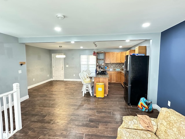 kitchen with a kitchen bar, open floor plan, freestanding refrigerator, and dark wood-type flooring