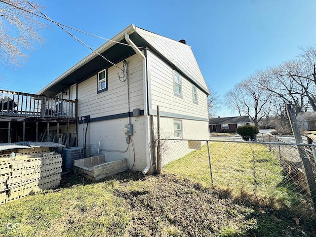 view of side of home with a deck, a yard, fence, and central AC