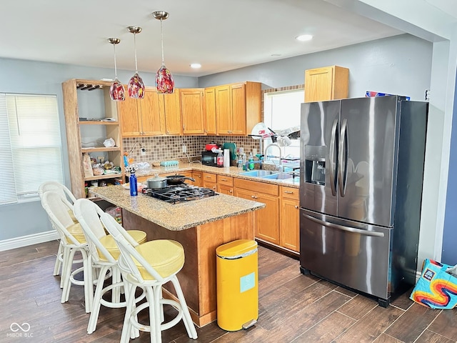 kitchen with a sink, plenty of natural light, stainless steel fridge with ice dispenser, and gas stovetop