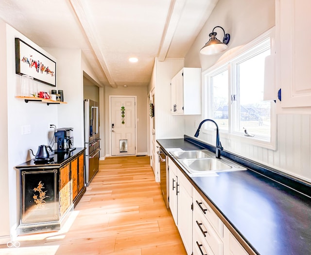 kitchen featuring a sink, dark countertops, white cabinets, and light wood finished floors