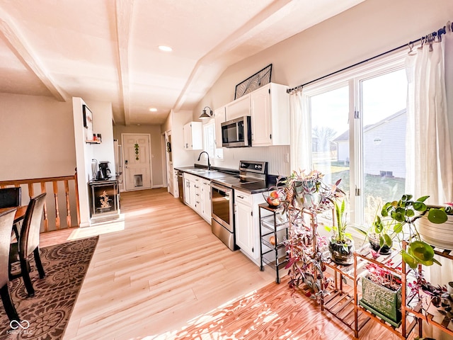 kitchen with dark countertops, appliances with stainless steel finishes, light wood-style flooring, and white cabinets