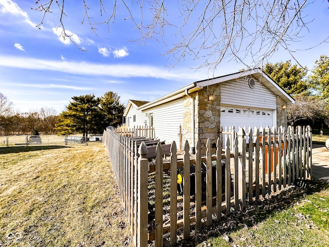 view of side of property featuring an outbuilding, fence, stone siding, and a detached garage