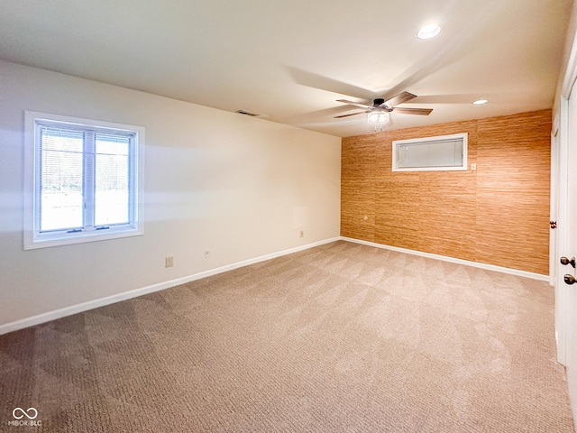 empty room featuring wooden walls, baseboards, light colored carpet, recessed lighting, and a ceiling fan