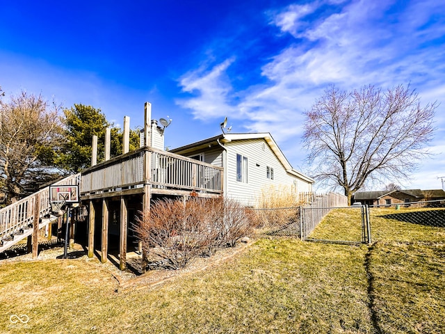 view of side of property featuring stairway, a lawn, a deck, and fence