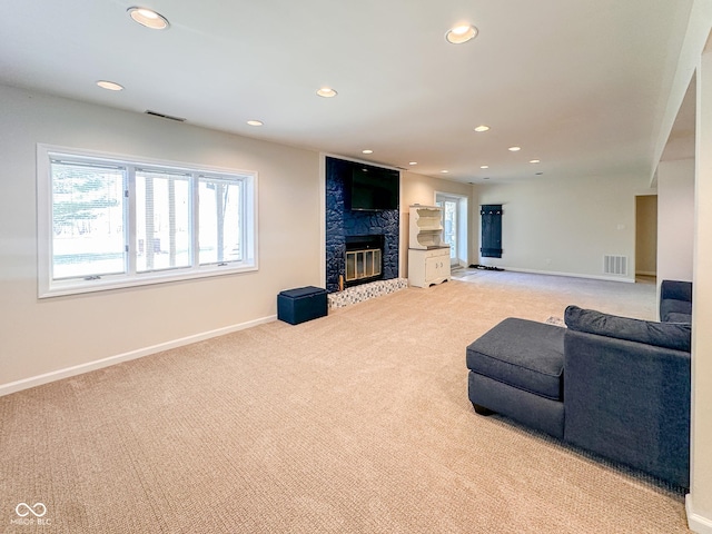 living area with visible vents, carpet flooring, and a glass covered fireplace