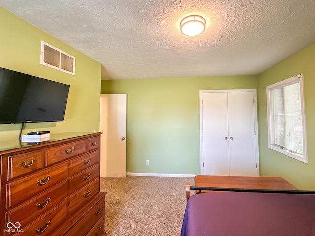 bedroom with visible vents, baseboards, carpet, a closet, and a textured ceiling