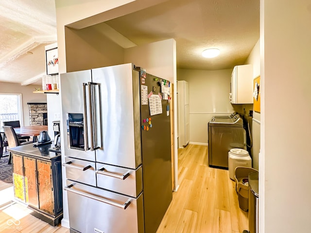 kitchen featuring light wood finished floors, a fireplace, high end fridge, a textured ceiling, and white cabinetry