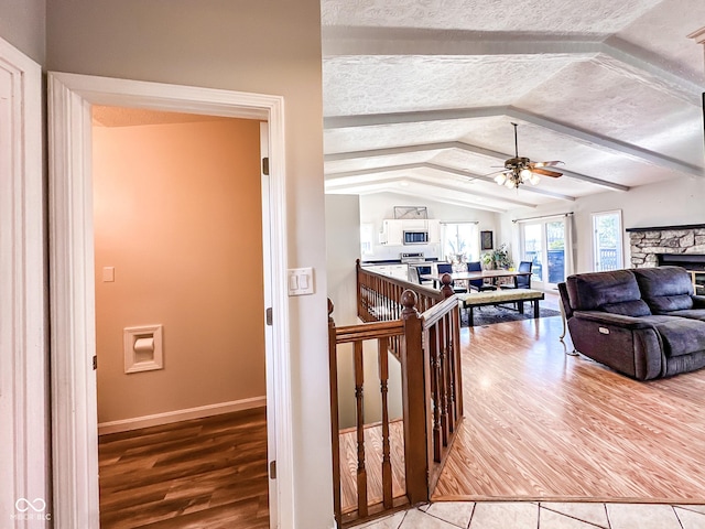 living room featuring a textured ceiling, wood finished floors, a fireplace, and vaulted ceiling