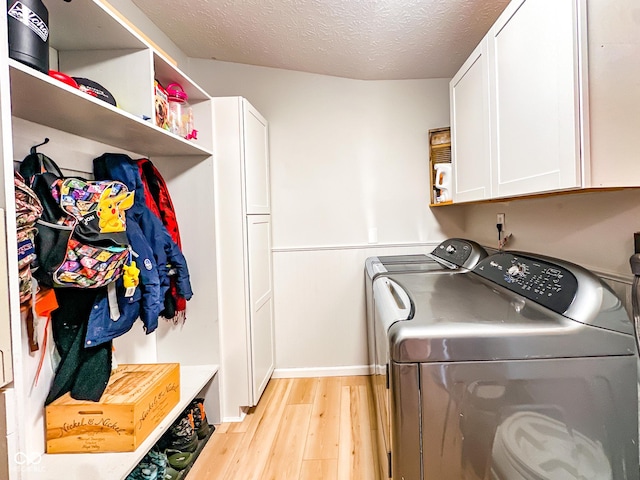 washroom with washer and clothes dryer, cabinet space, light wood finished floors, and a textured ceiling