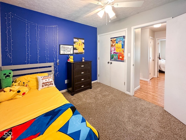 carpeted bedroom featuring baseboards, a textured ceiling, and ceiling fan