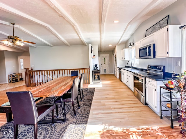 kitchen with white cabinetry, dark countertops, light wood-style flooring, and appliances with stainless steel finishes