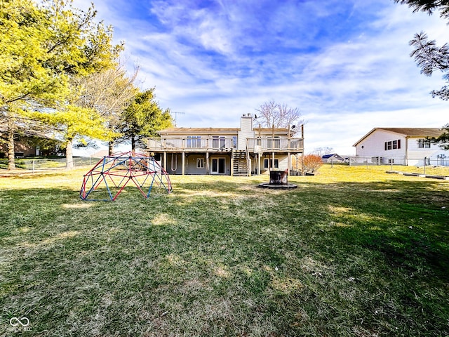 rear view of house with a lawn, a deck, fence, stairway, and a fire pit