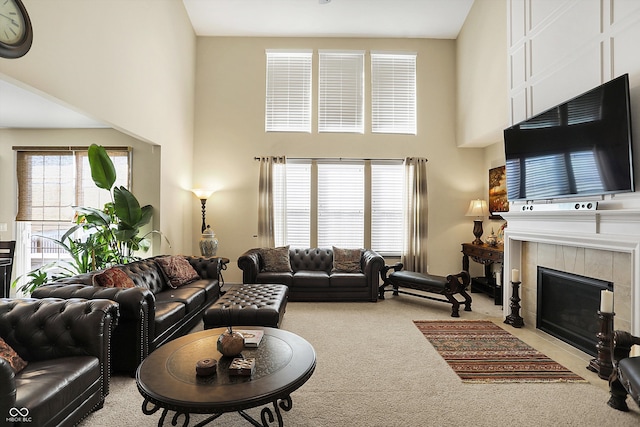 living area with carpet floors, a towering ceiling, and a fireplace