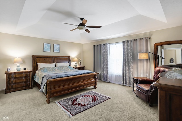 bedroom featuring light carpet, a raised ceiling, and a ceiling fan