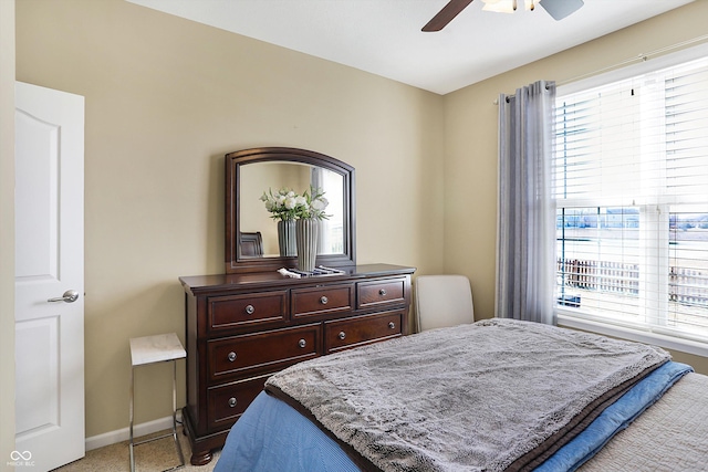 bedroom featuring multiple windows, a ceiling fan, light colored carpet, and baseboards