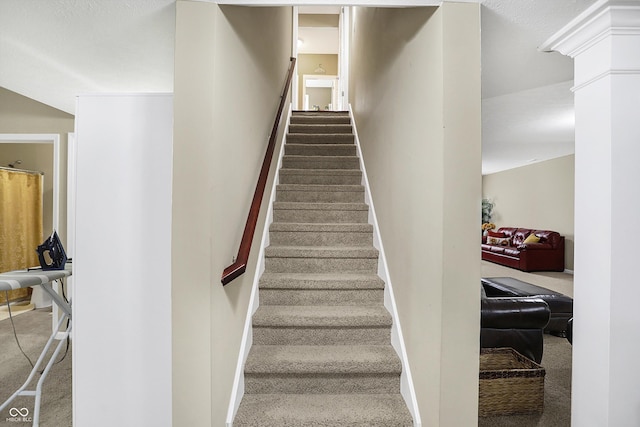 stairs featuring baseboards, carpet floors, and ornate columns