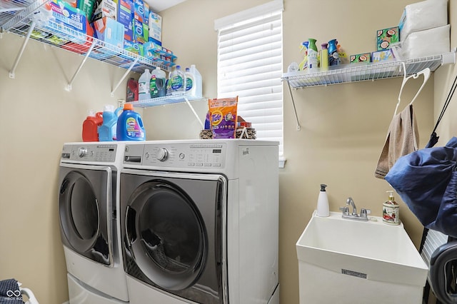 clothes washing area featuring a sink, separate washer and dryer, and laundry area