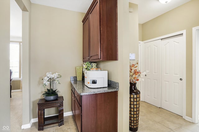 interior space featuring dark stone counters, light tile patterned floors, and baseboards