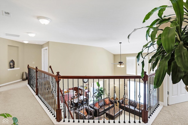 hallway with an upstairs landing, visible vents, baseboards, and carpet