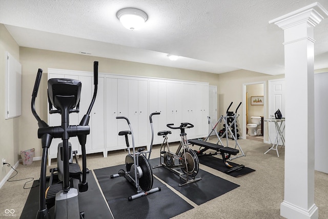 workout room featuring baseboards, carpet flooring, a textured ceiling, and ornate columns