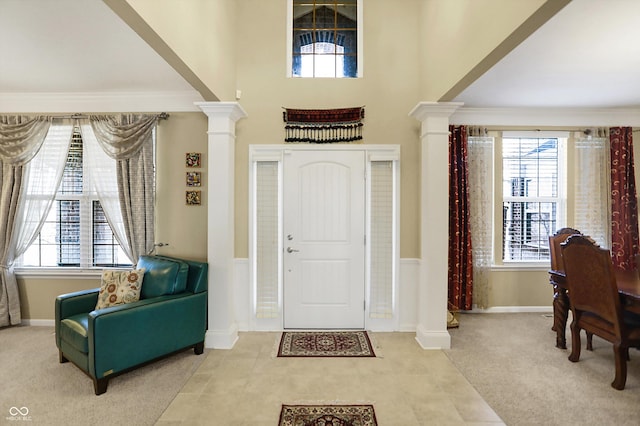 entryway featuring carpet flooring, baseboards, and decorative columns