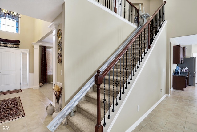 stairs featuring ornate columns, tile patterned floors, and a towering ceiling