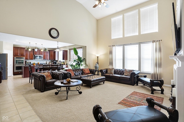 living room featuring light tile patterned floors, a fireplace, high vaulted ceiling, and ceiling fan