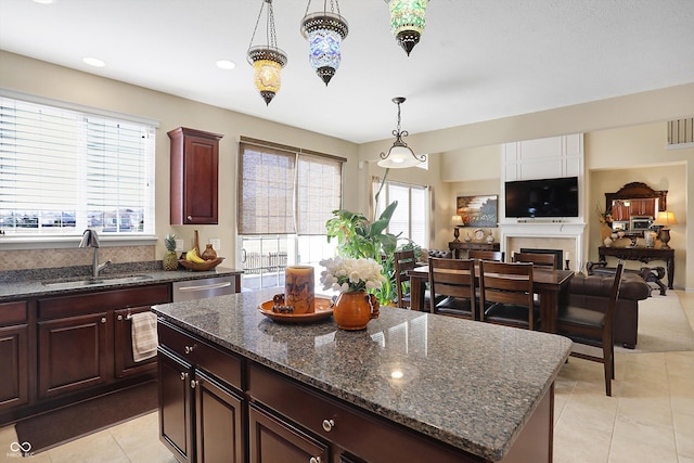 kitchen featuring pendant lighting, dishwasher, a fireplace, light tile patterned flooring, and a sink