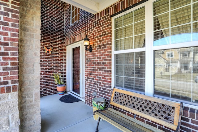 doorway to property featuring brick siding and covered porch