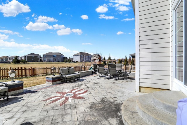 view of patio featuring outdoor dining space, fence, a residential view, and an outdoor hangout area