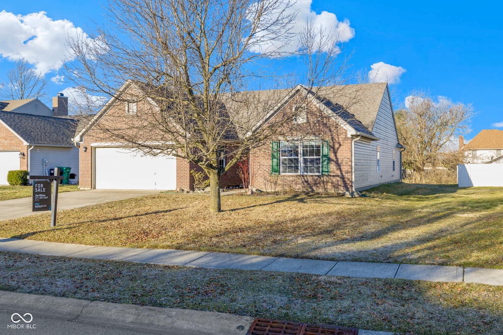 view of front of property with brick siding, driveway, an attached garage, and a front lawn