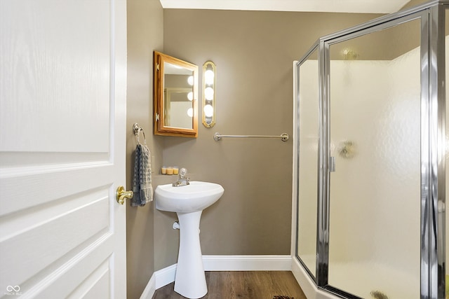 bathroom featuring baseboards, wood finished floors, and a stall shower