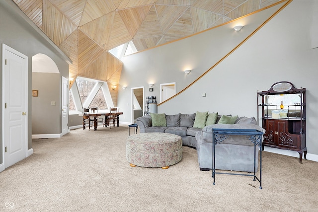 carpeted living area with arched walkways, a high ceiling, and baseboards