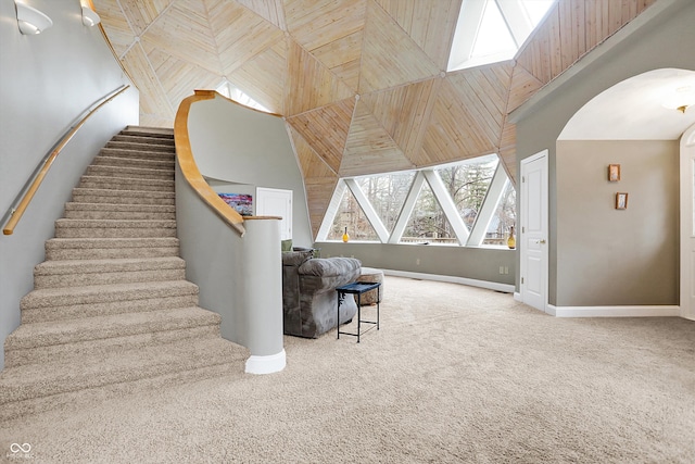 stairway with carpet, baseboards, a towering ceiling, and arched walkways